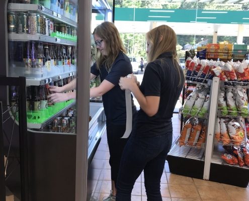 Two Teenage Girls Add Labels To Alcoholic Beverages To Prevent Underage Alcohol Abuse